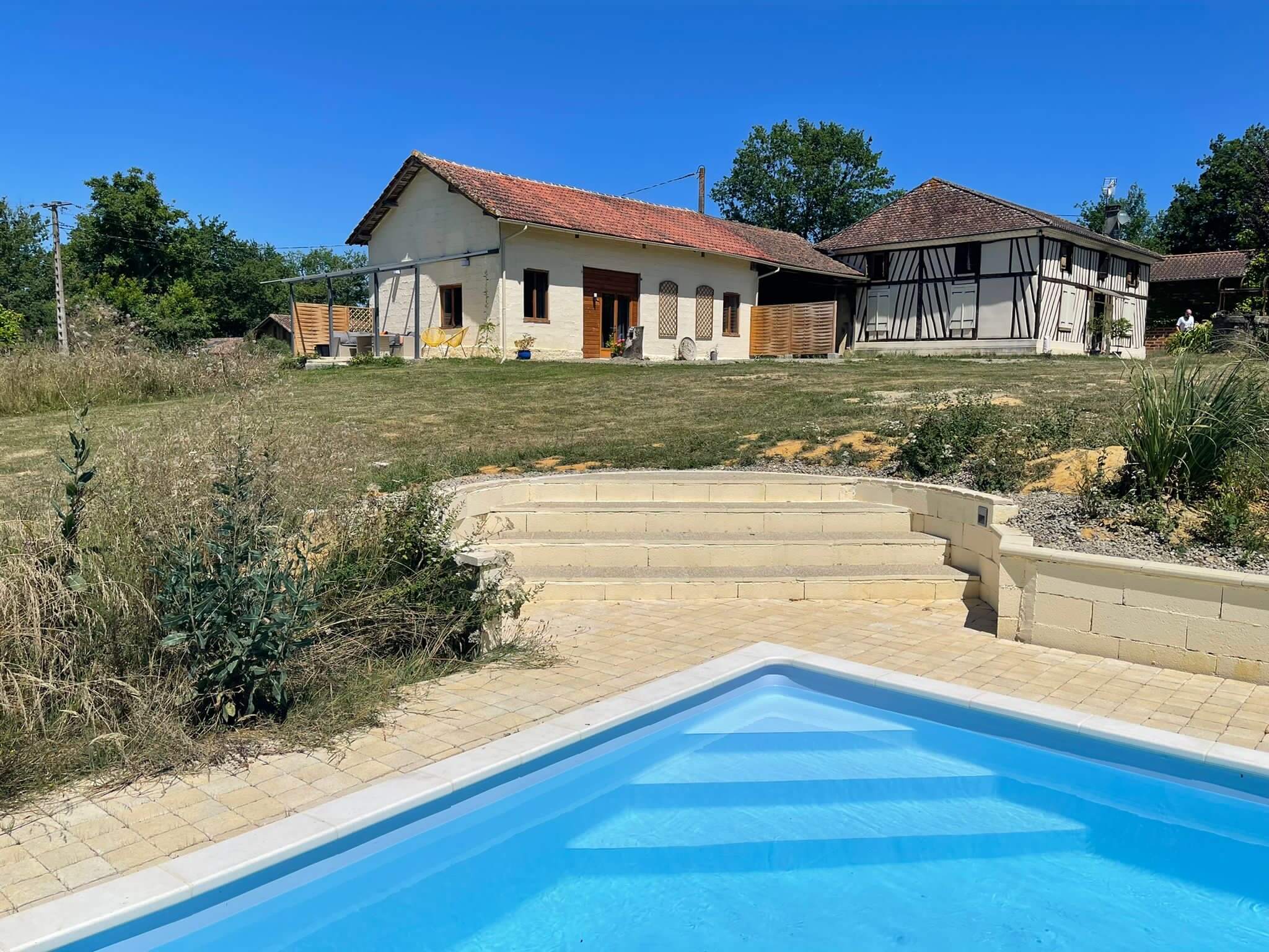 A pool with a blue tiled bottom and a house in the background.