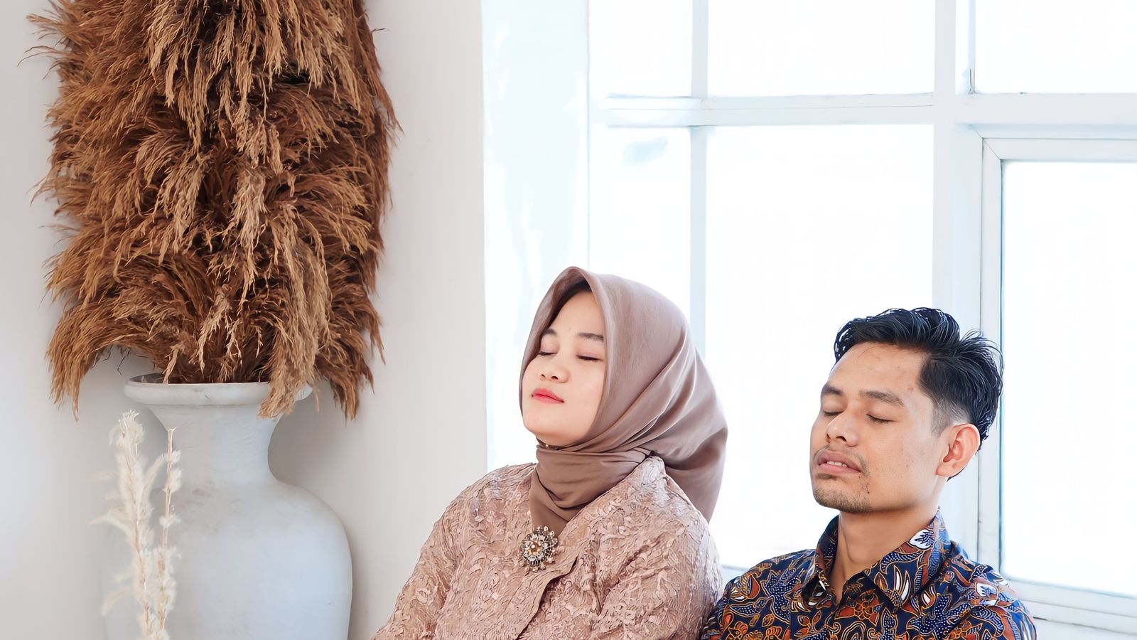 Asian couple sitting eyes closed on couch, peaceful