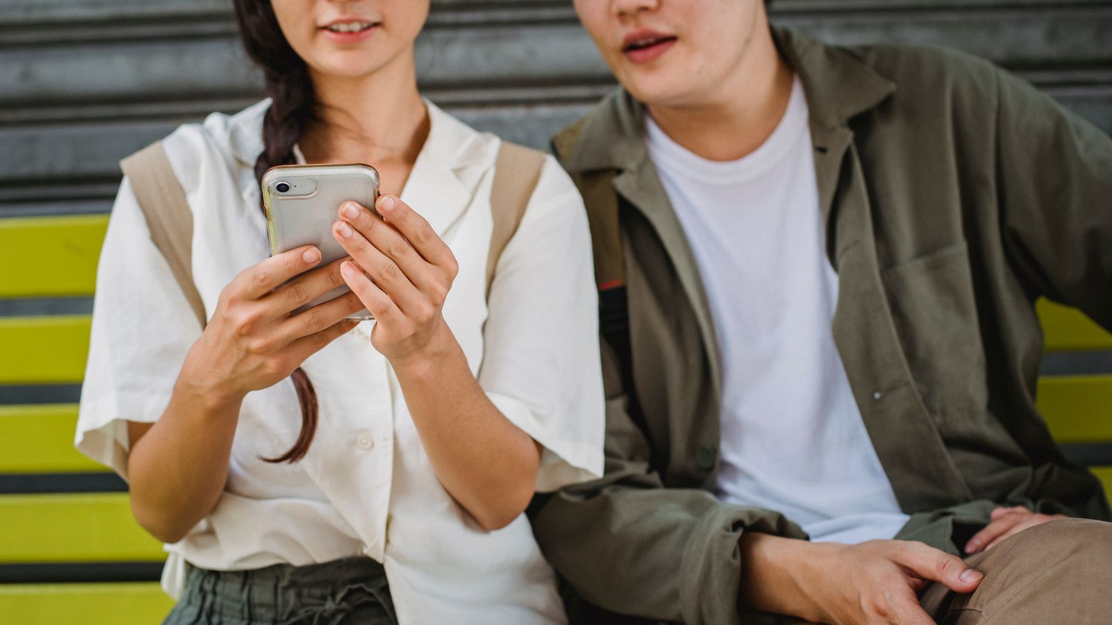 Asian couple browsing smartphone on bench