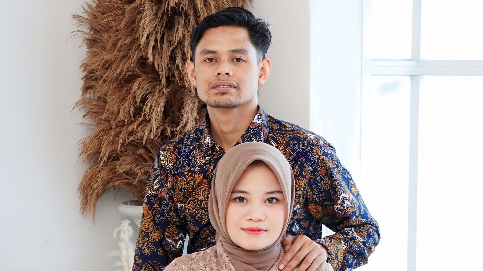 Asian couple sitting together by window, traditional attire