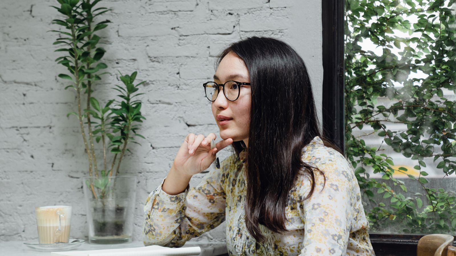 Thoughtful young Asian businesswoman working on project, cafe