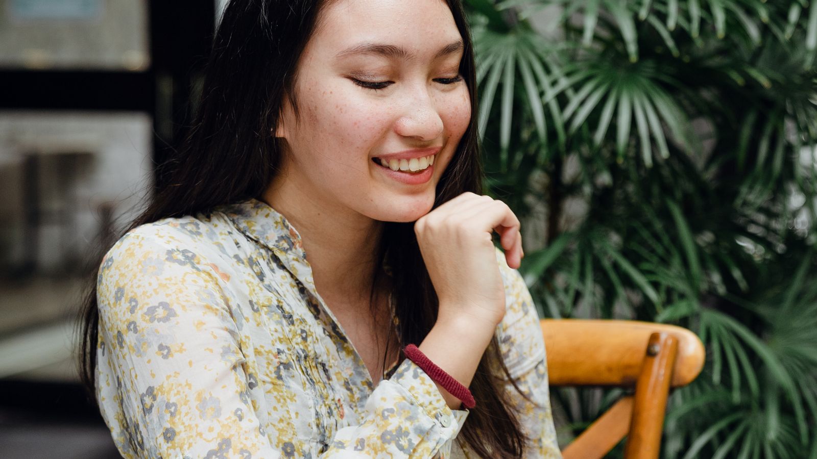Cheerful young Asian woman calling on smartphone, outdoor cafe