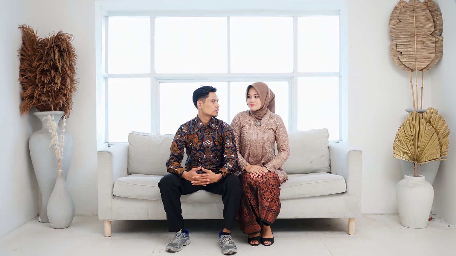 Asian couple sitting together on couch, traditional attire