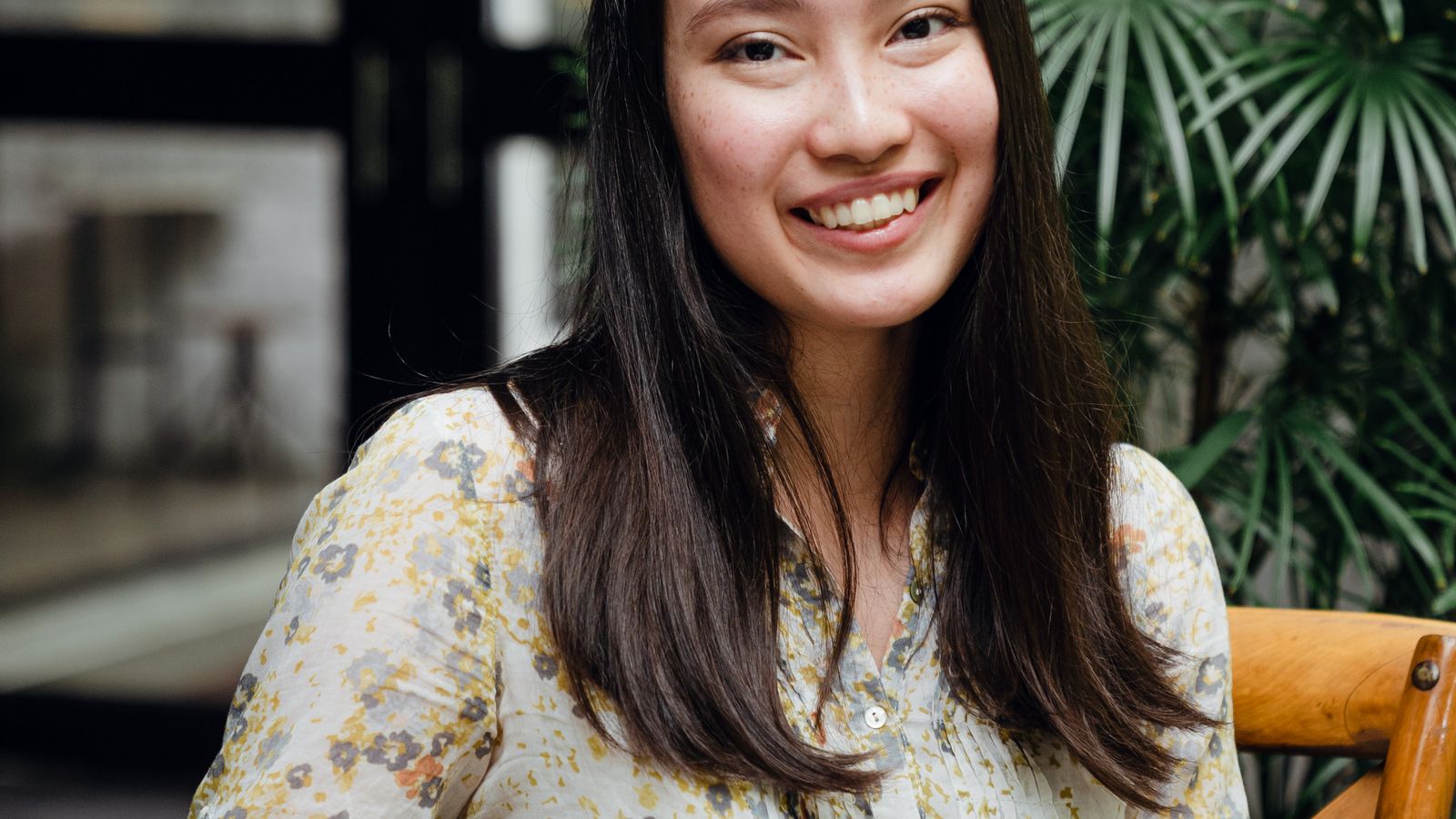 Smiling young Asian woman with smartphone, coffee break street cafe