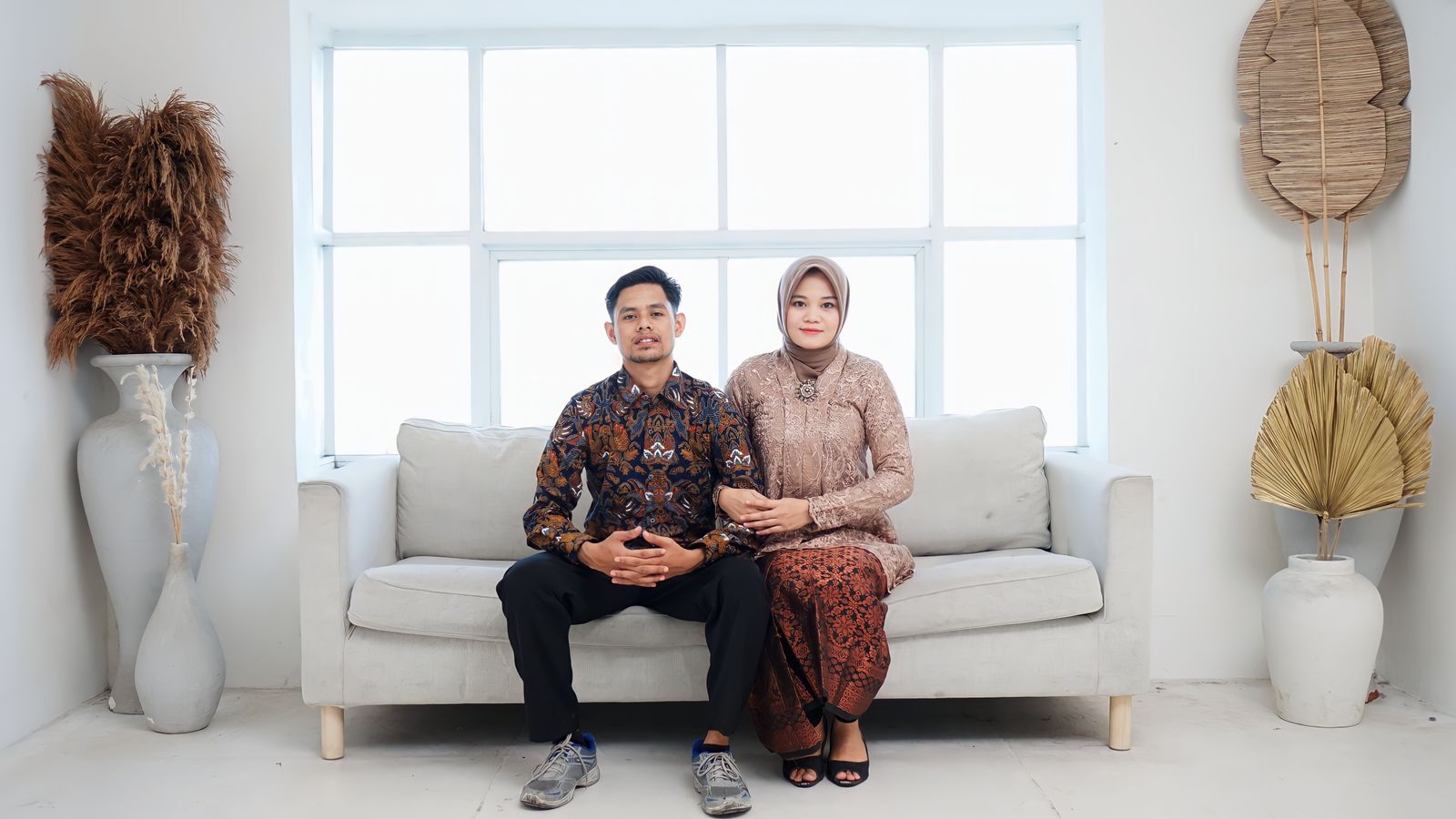 Asian couple in traditional attire sitting on couch