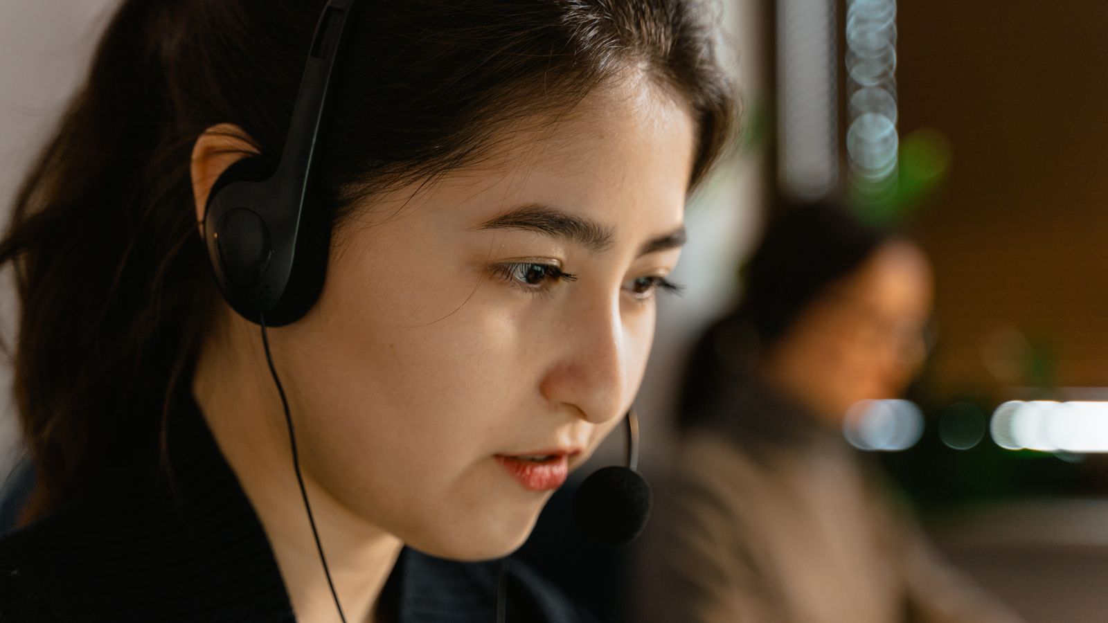 Focused Asian woman headset, customer support office