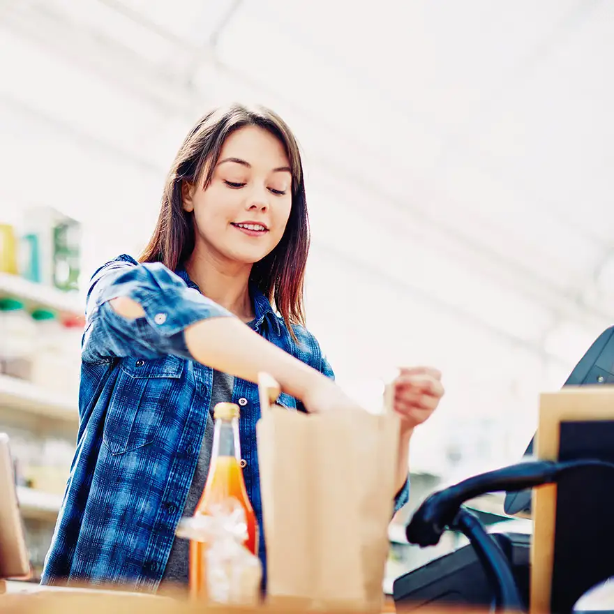 Schülerin als Einpackhilfe an der Kasse