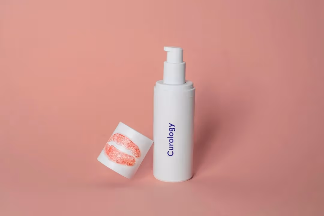 bottle of curology with the cap off and lipstick lips on the cap