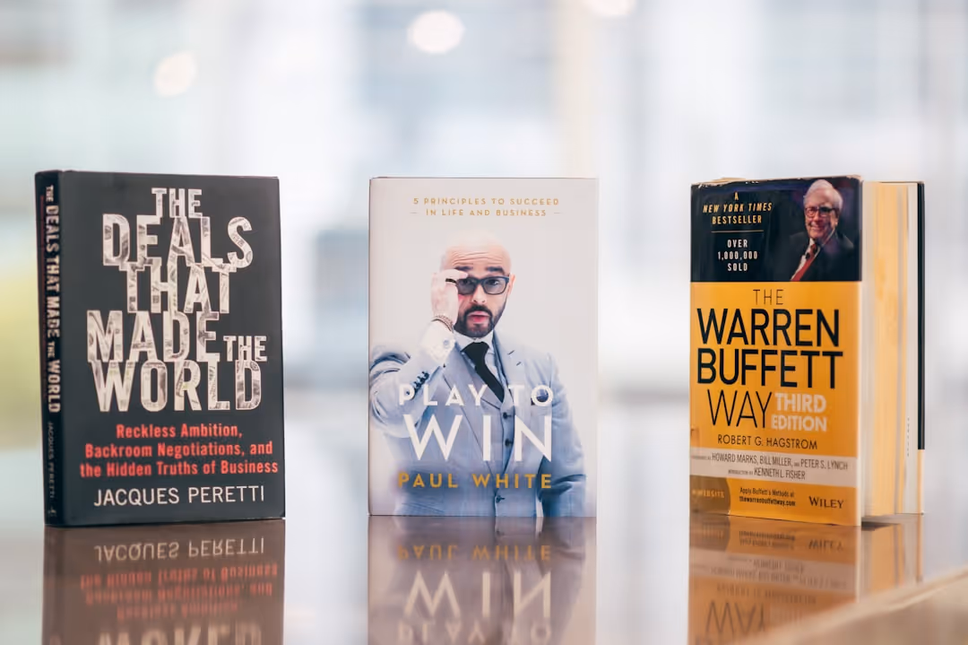 Three business books on a reflective table, representing resources to find podcast guests in the business world.