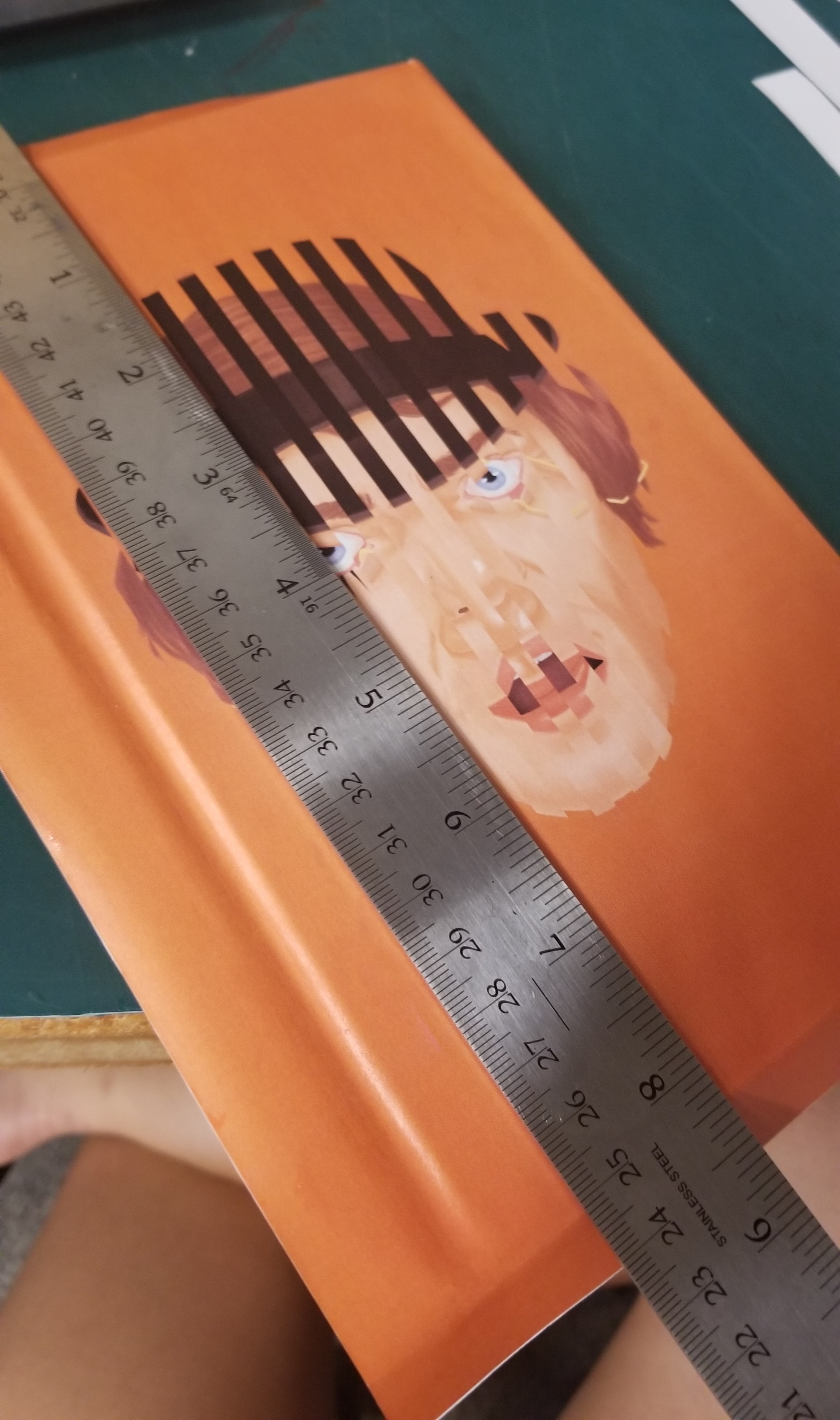 Euni using a metal ruler to flatten and glue the printed illustration to a book cover