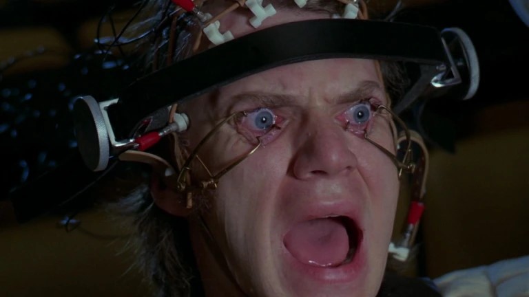 A frame from Stanley Kubrick's film adaptation of Clockwork Orange showing  Alex with his eyes being forced open, looking horrified