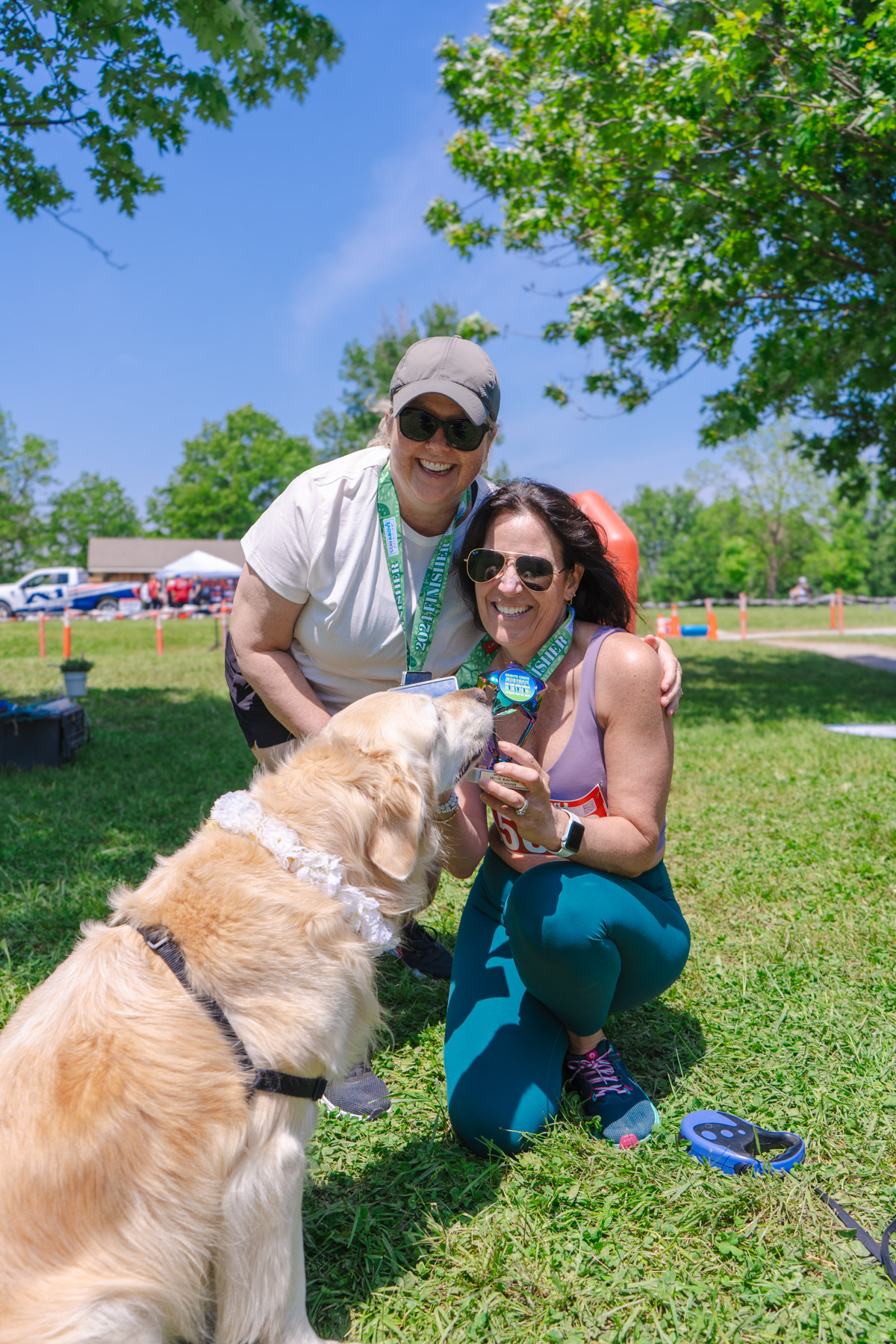 A Golden Retriever inspects a medal its owner holds up after completing a 5k run