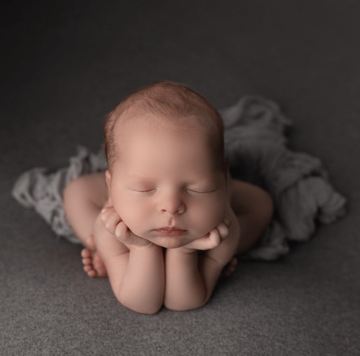a baby sleeps in a newborn photographer studio in a froggy pose