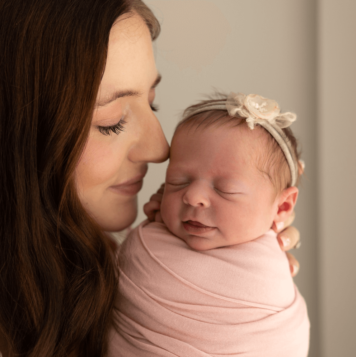a mom with brown hair smiles and nuzzles her baby girl who is also smiling newborn photography billings mt
