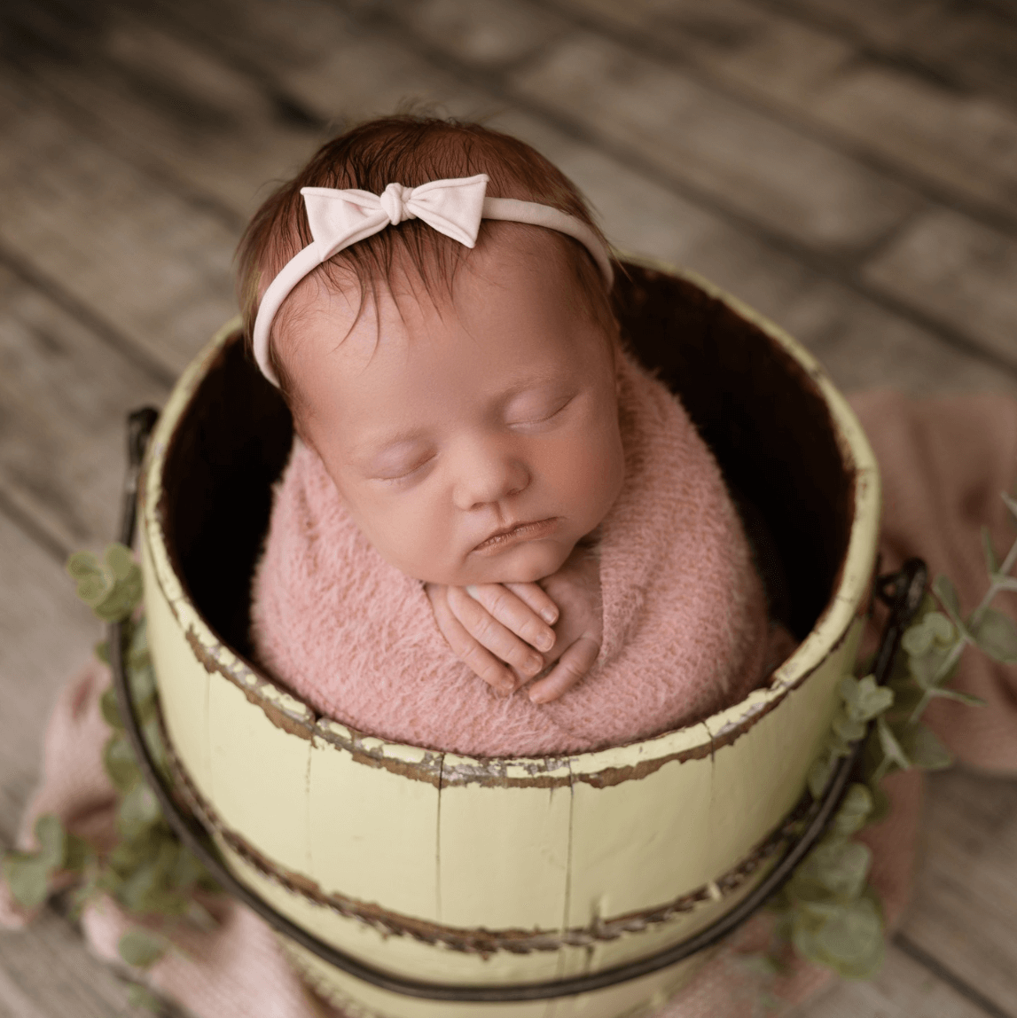 beautiful baby infant girl sleeps in a brown bucket in a newborn photographer studio billings mt