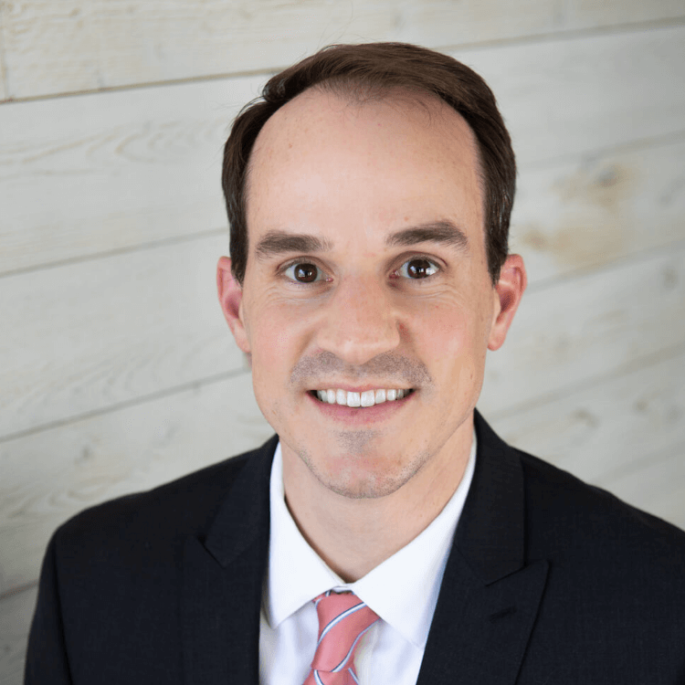 young male in business suit smiles at camera in professional headshot square social
