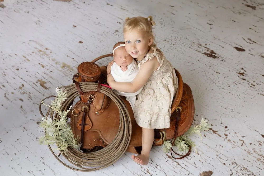 newbown baby with sister and saddle in studio eMarie Photography in Billings, MT