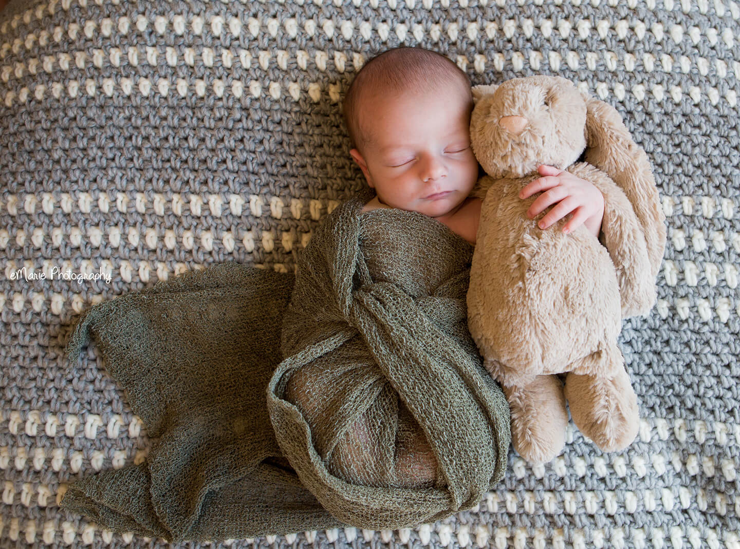 Newborn baby snuggles stuffed rabbit