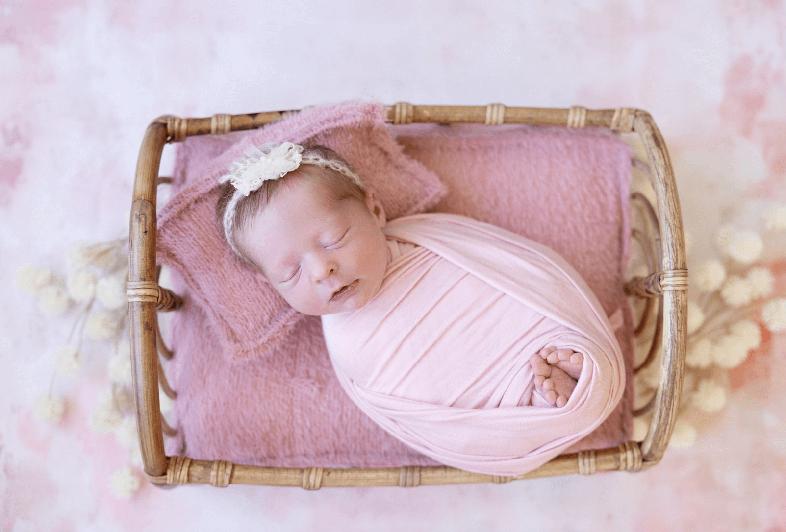 gorgeous little baby girl newborn sleeps with her toes peeking out of her swaddle. a baby girl sleeps in a studio wicker basket. a cute older sister lovingly snuggles her sleeping newborn brother. best newborn photographer in Billings MT