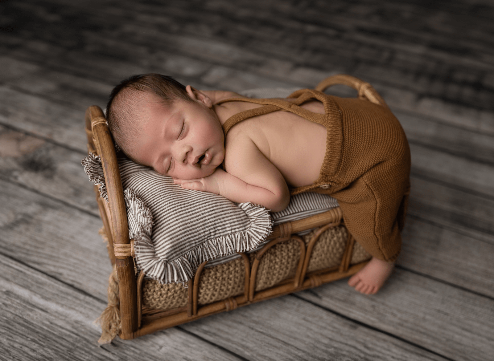 cute little infant boy in suspenders sleeps in a photography studio. a baby girl sleeps in a studio wicker basket. a cute older sister lovingly snuggles her sleeping newborn brother. best newborn photographer in Billings MT