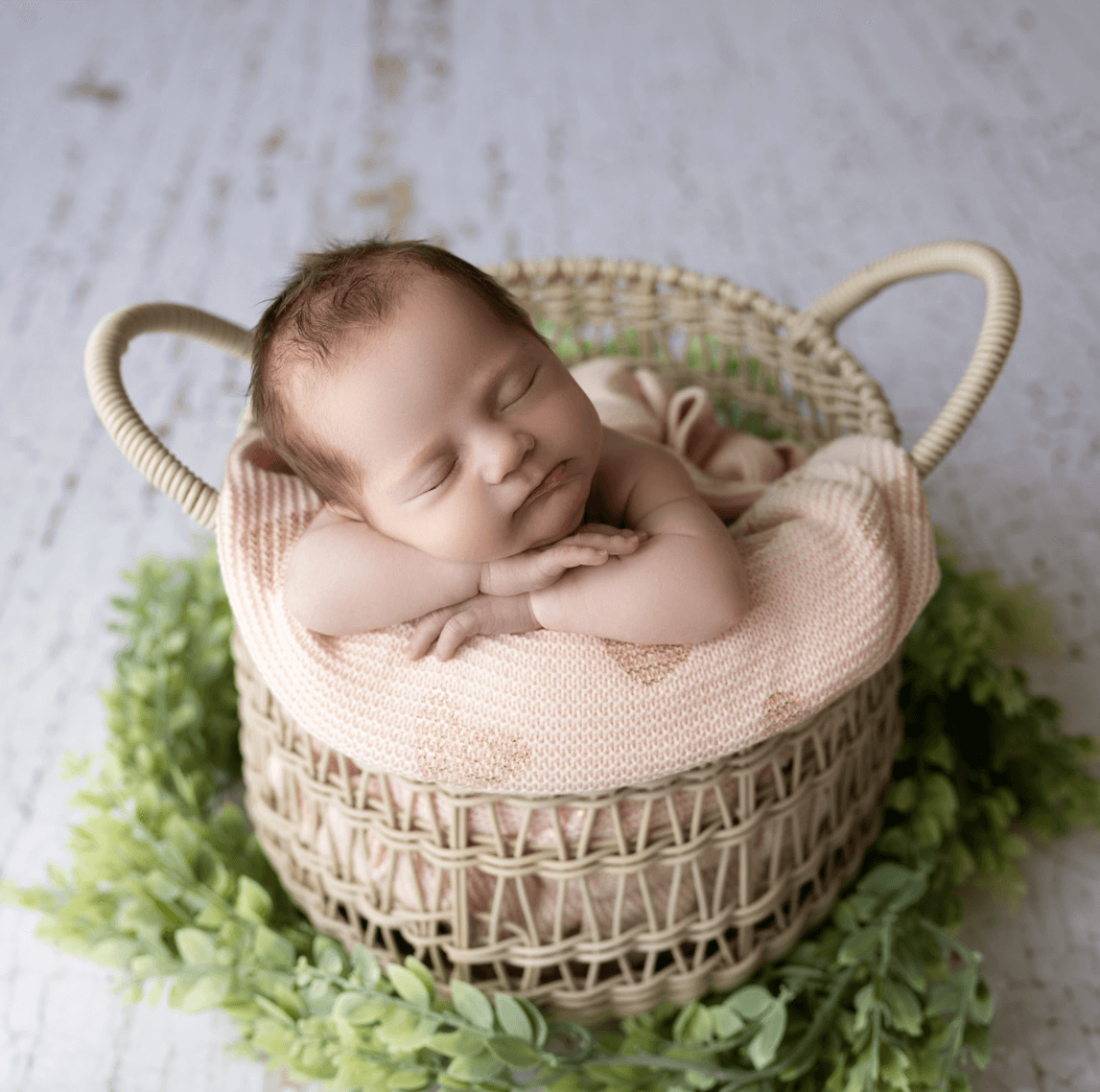 close up of a sleeping infant in a wicker basket. a cute older sister lovingly snuggles her sleeping newborn brother. Billings MT newborn photography