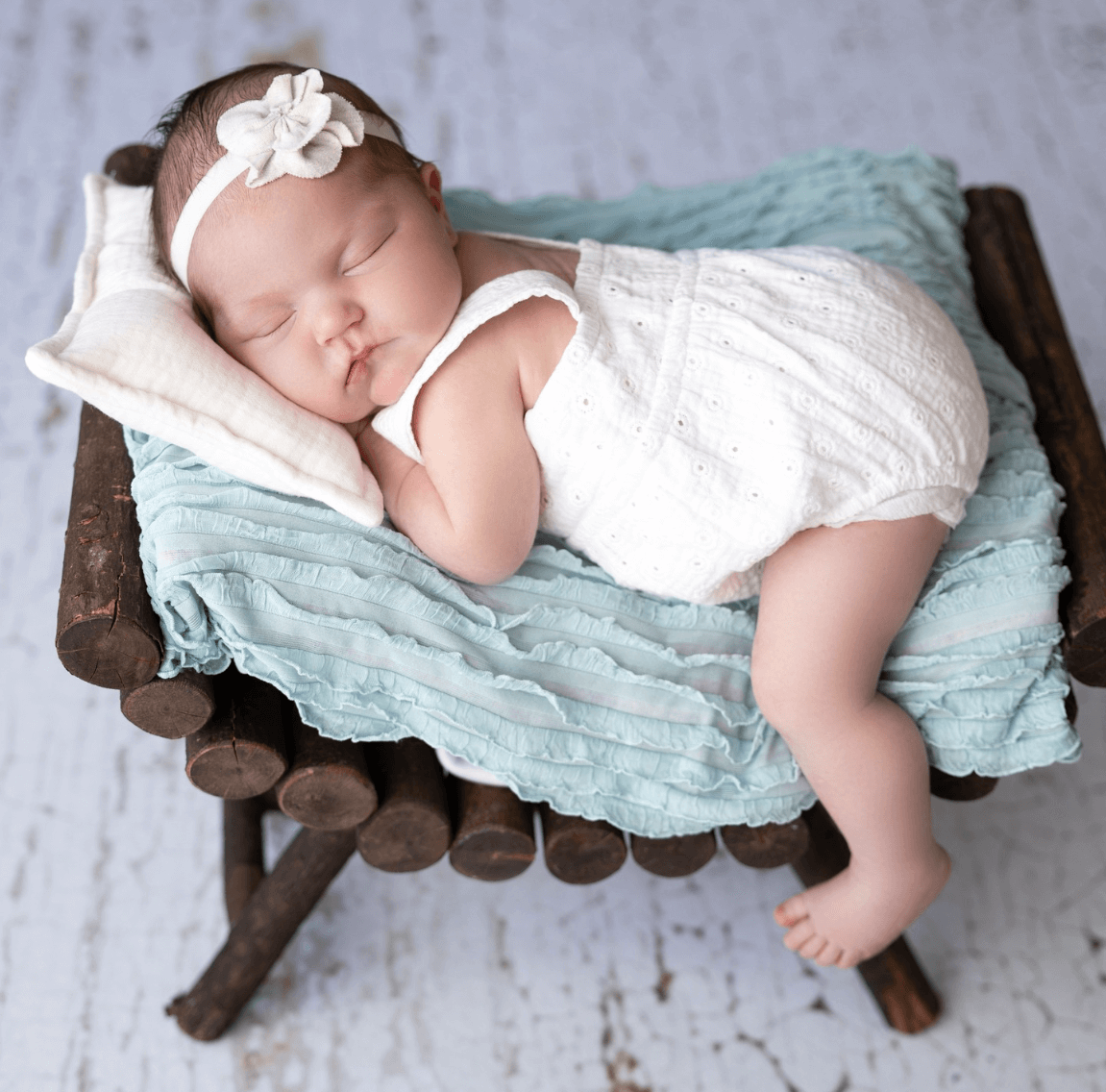 newborn infant girl lounges in a photography studio in Billings MT on a wooden bench