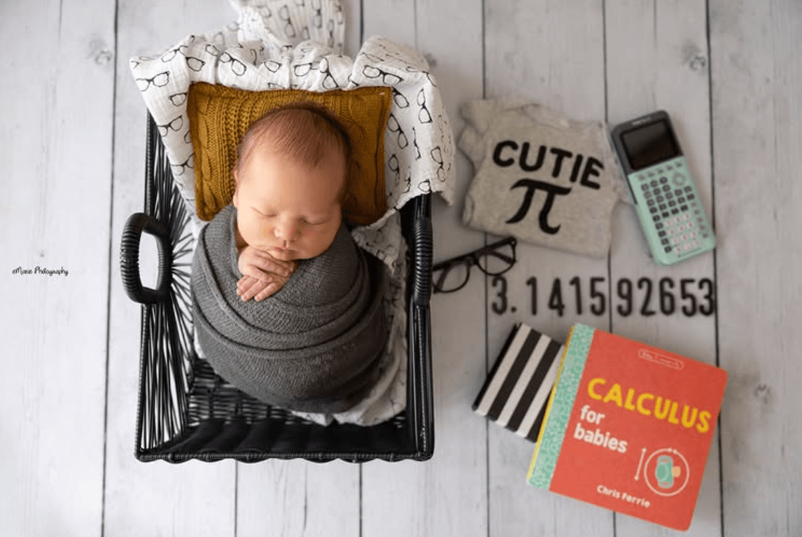 fun newborn photography props with a play on the math term pi. a baby girl sleeps in a studio wicker basket. a cute older sister lovingly snuggles her sleeping newborn brother. best newborn photographer in Billings MT