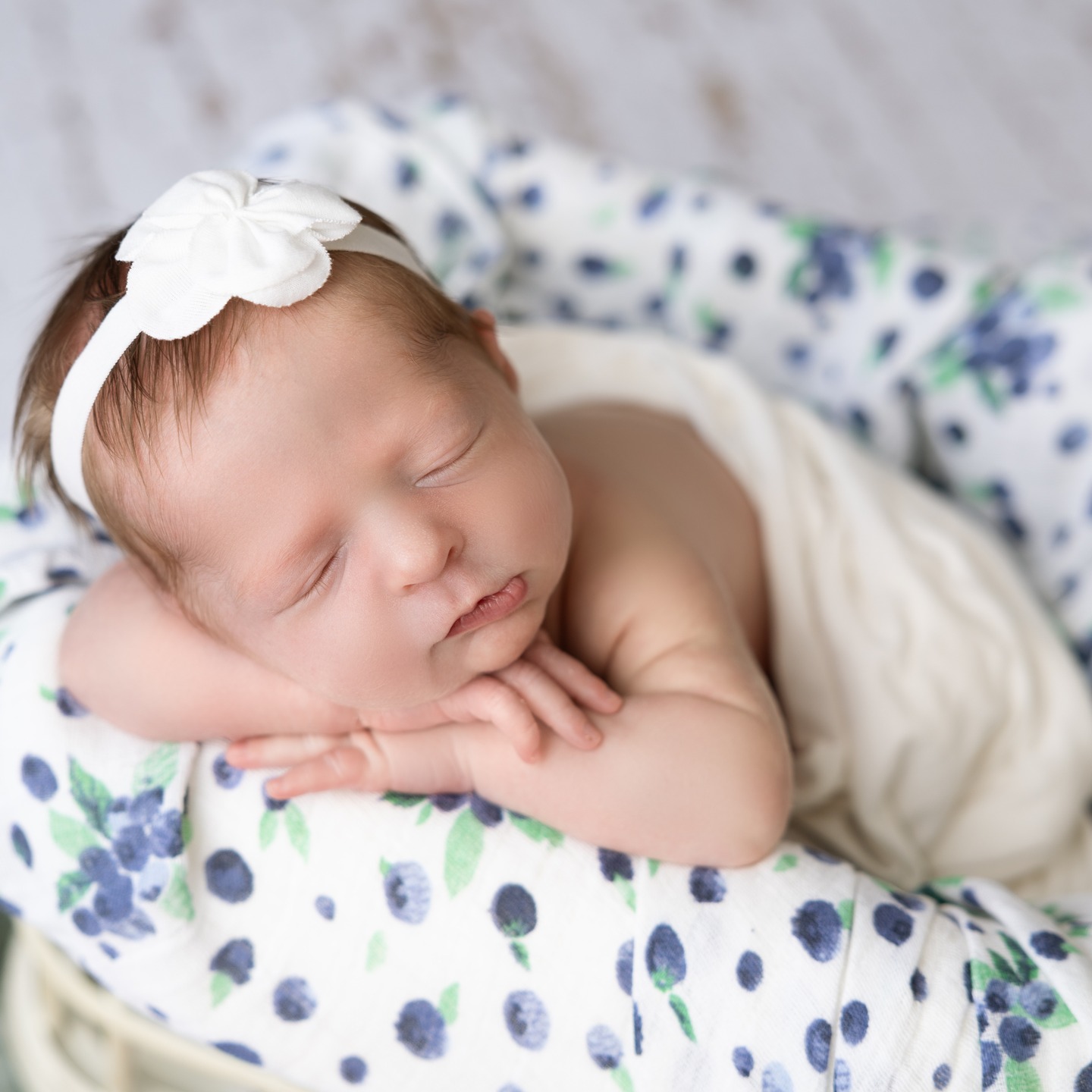 sweet baby girl sleeps with white bow on head in photography studio