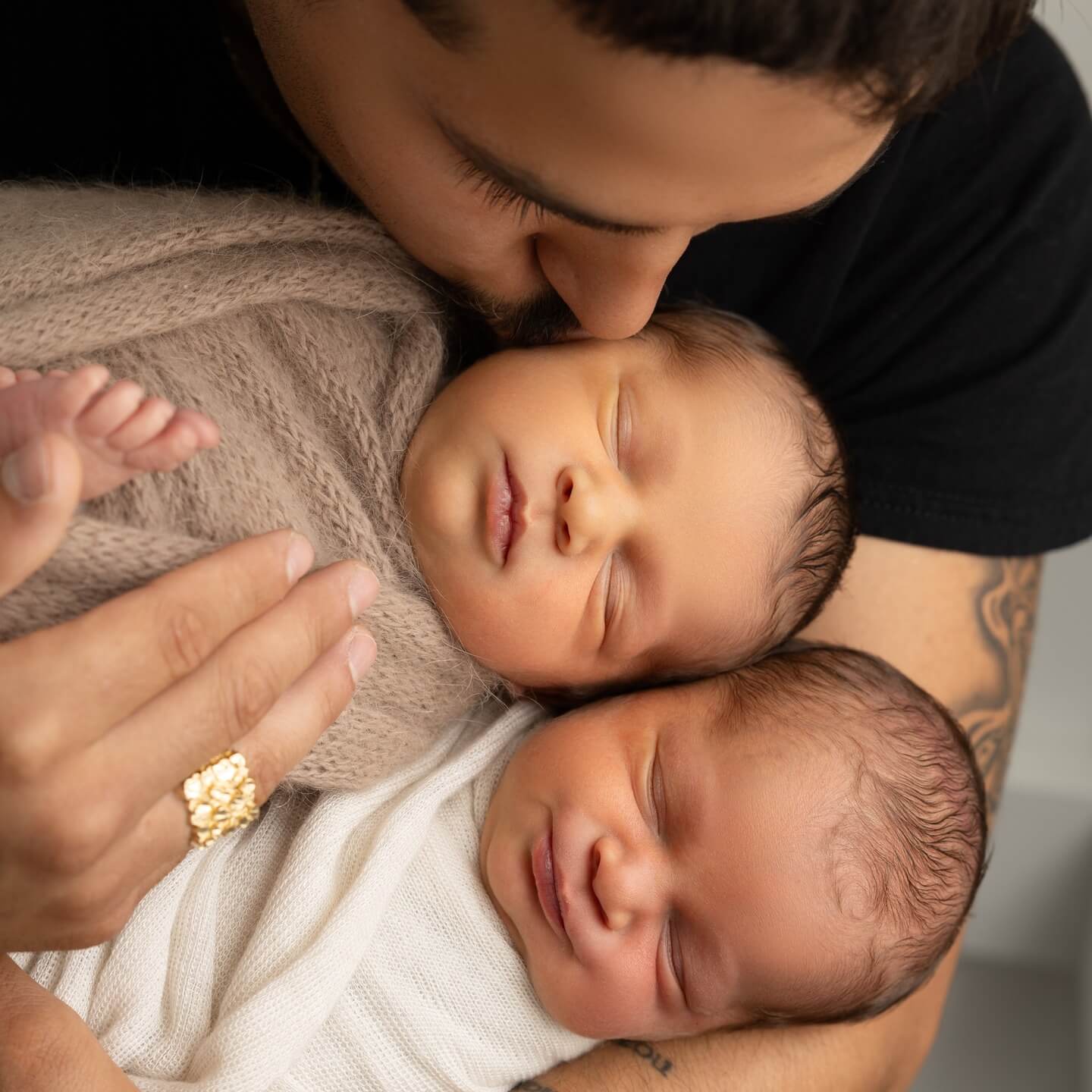 father holds and kisses twins in newborn photography session