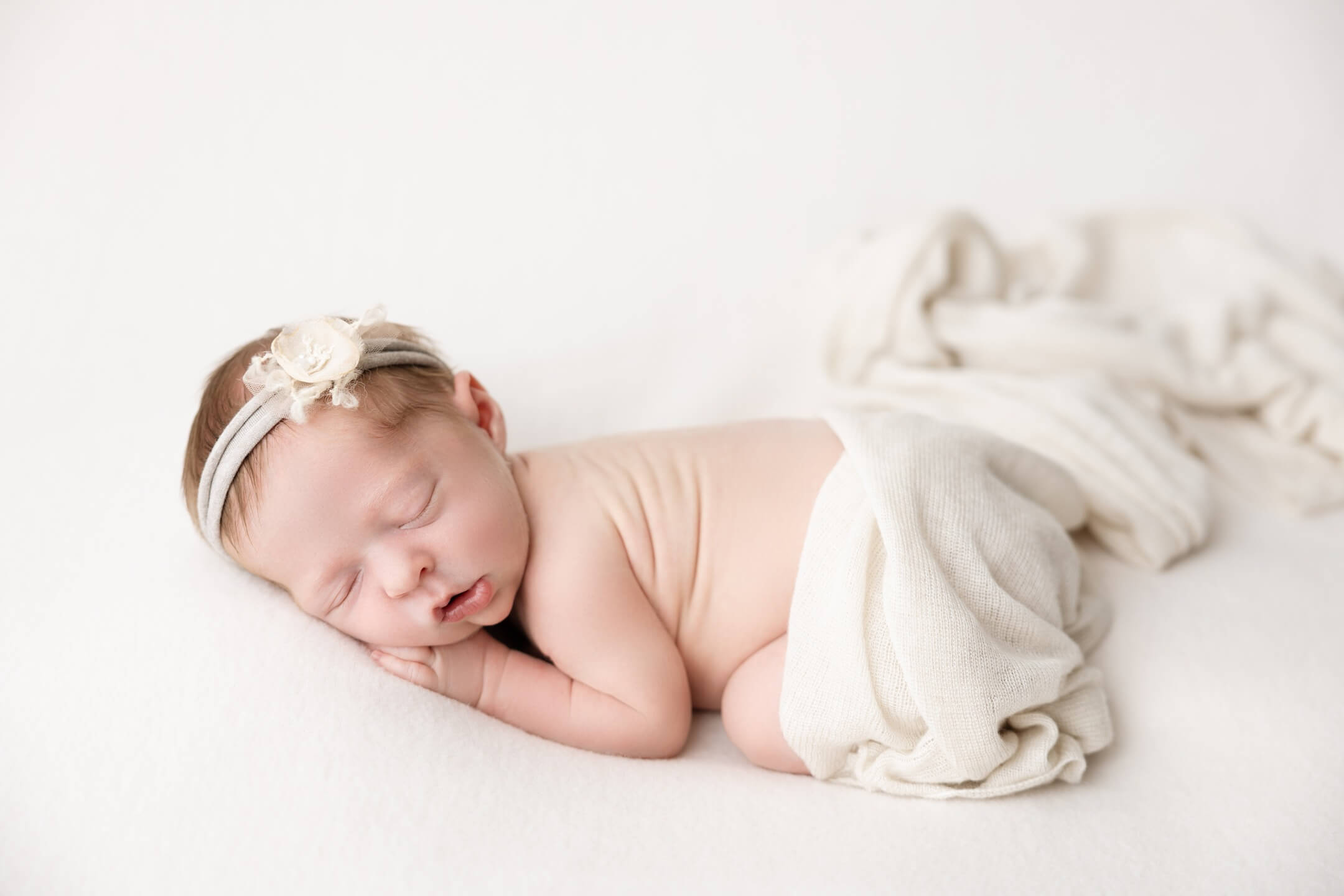 newborn baby girl sleeps in white bow on white background newborn photography billings mt