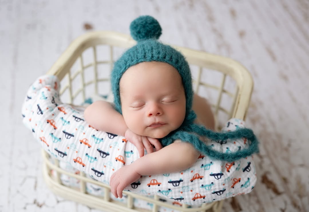 little boy in blue knit hat sleeps in car blanket in basket newborn photographer billings mt