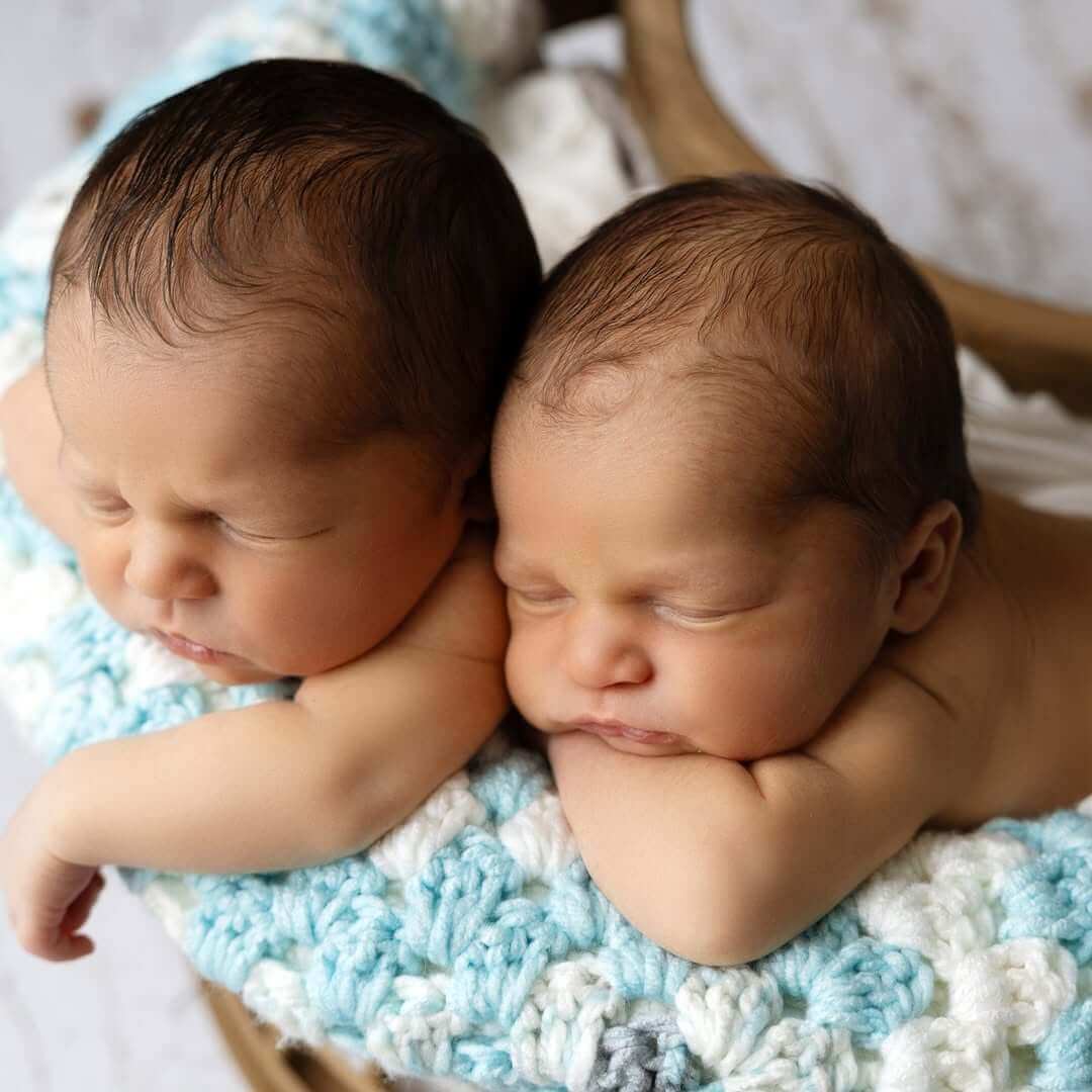 newborn infant twins snuggle with one another on a white blanket newborn photographer billings mt