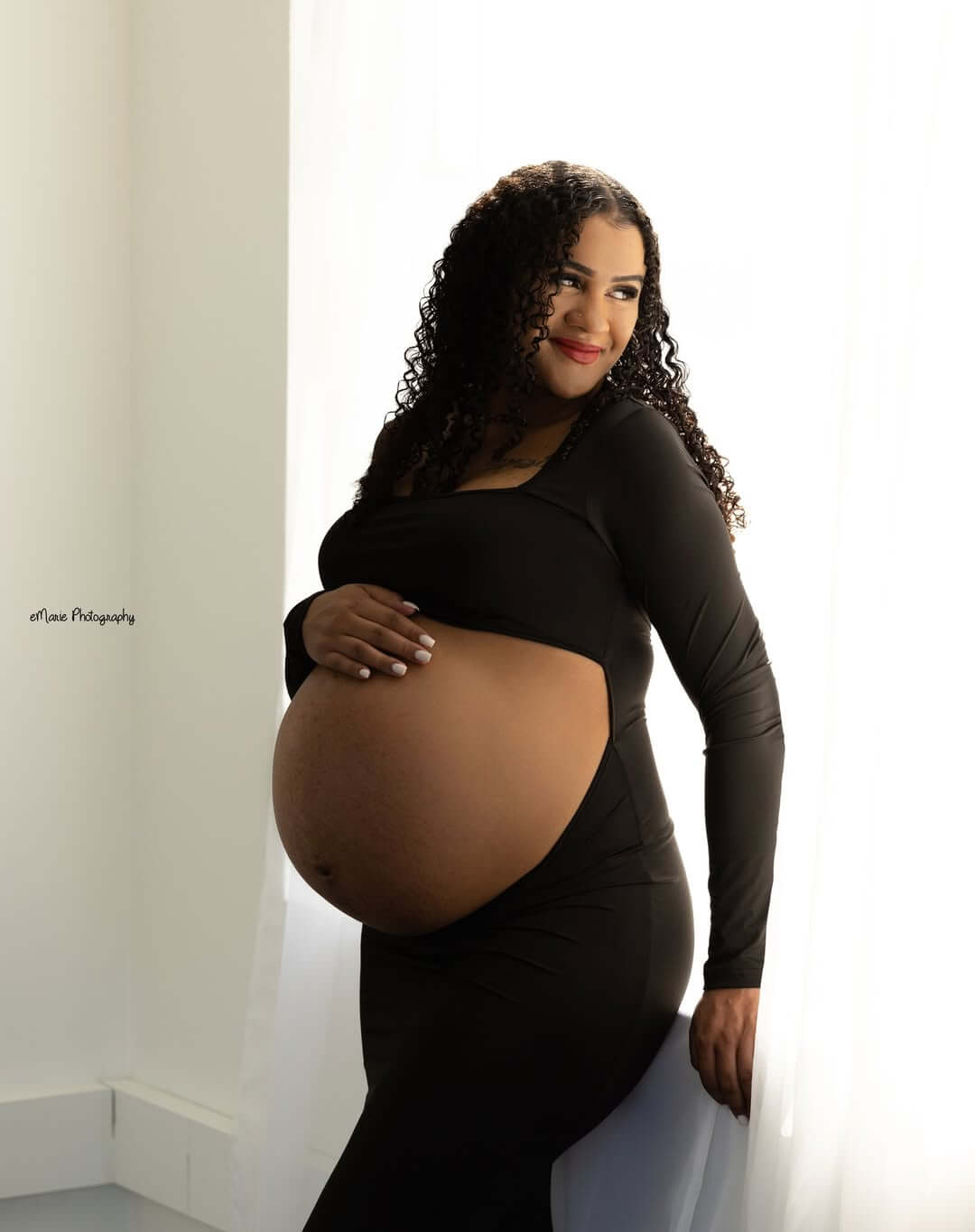 beautiful maternity session showing bare belly as she smiles in studio
