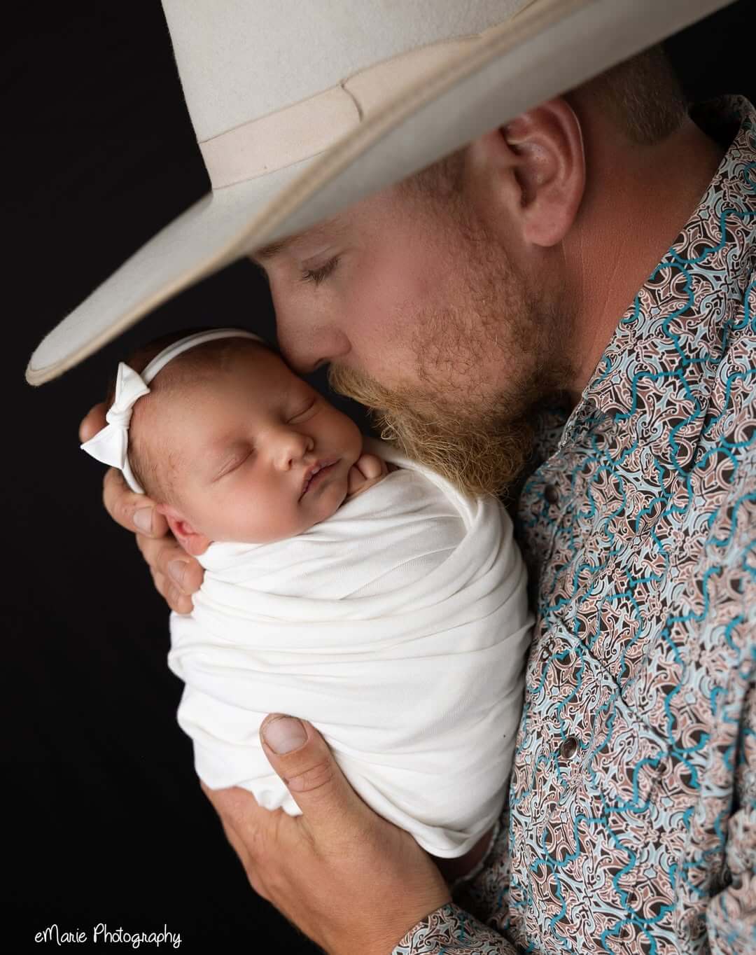 cowboy kisses baby daughter in white bow in emarie photography studio