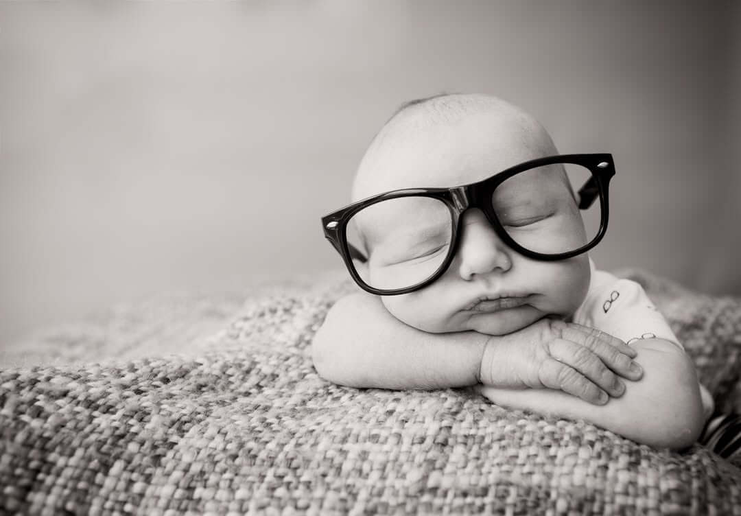 cute newborn baby boy sleeps with glasses on blanket in black and white