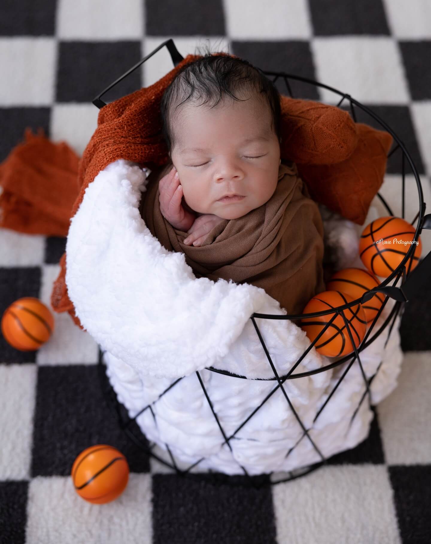 newborn baby boy sleeps in basket with mini basketballs all around newborn photography billings mt