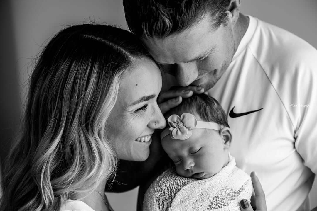 athletic couple smiles and snuggles their sleeping newborn billings mt newborn photography