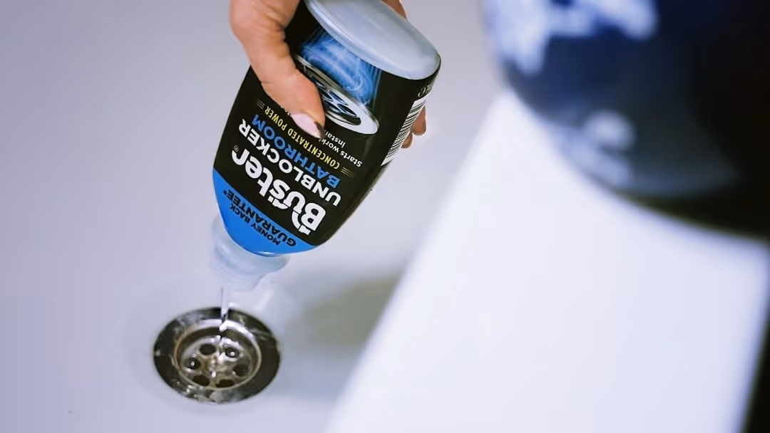 A photo of a person pooring Buster Bathroom Unblocker in a drain