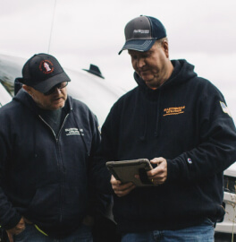 Two wastewater utility operators looking at a tablet together outdoors near a vehicle