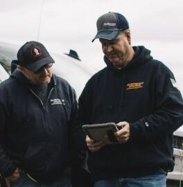 Two water utility operators outdoors reviewing infrastructure data on a tablet together