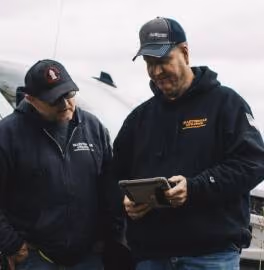Two water utility operators outdoors reviewing infrastructure data on a tablet together