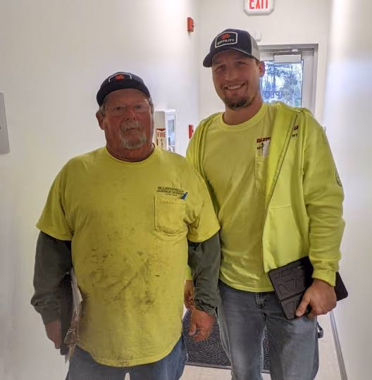 Father and son in hi-vis vests standing together at a water utility — generational knowledge transfer