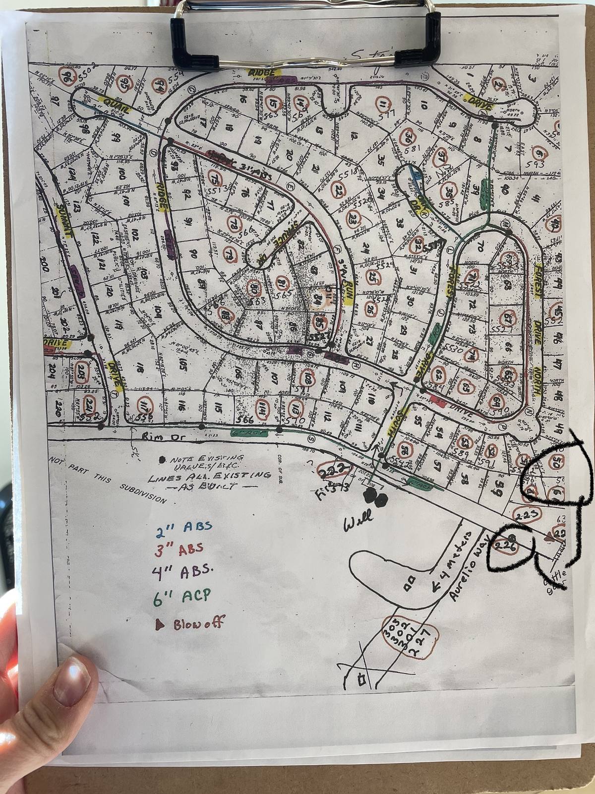 Paper subdivision as-built drawings on a clipboard, the kind of utility asset database that drifts away from reality