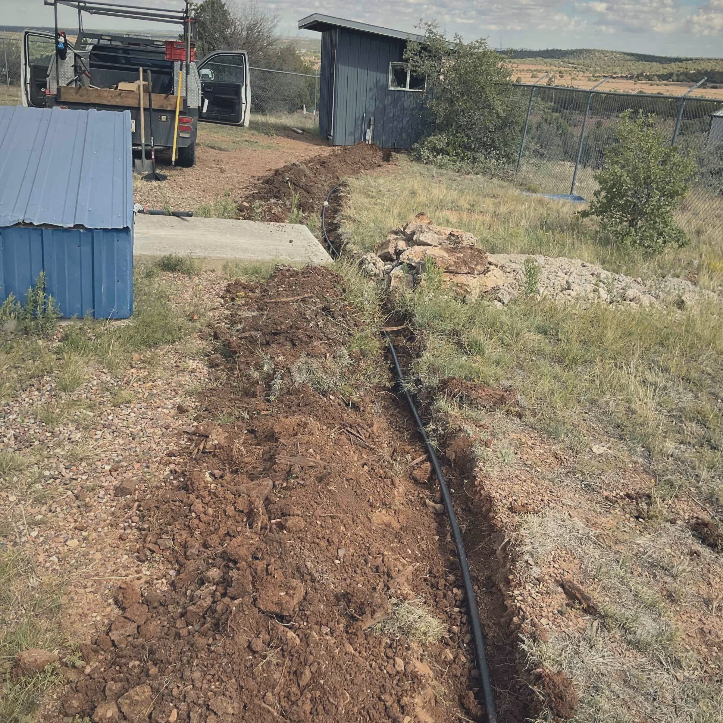 Open service line trench running from the water main toward a building