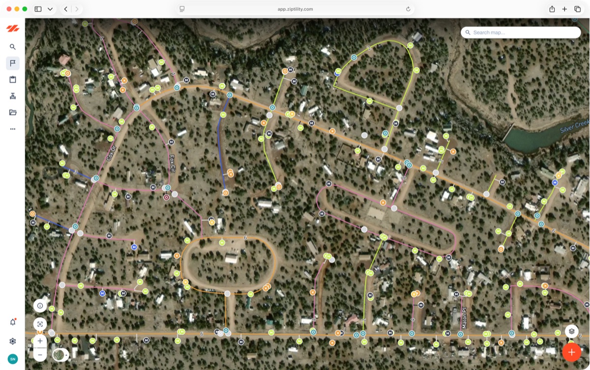 The Ziptility app in a desktop browser, showing a satellite view of a neighborhood with pipe lines drawn in color and dozens of asset markers along them, some of them plain gray