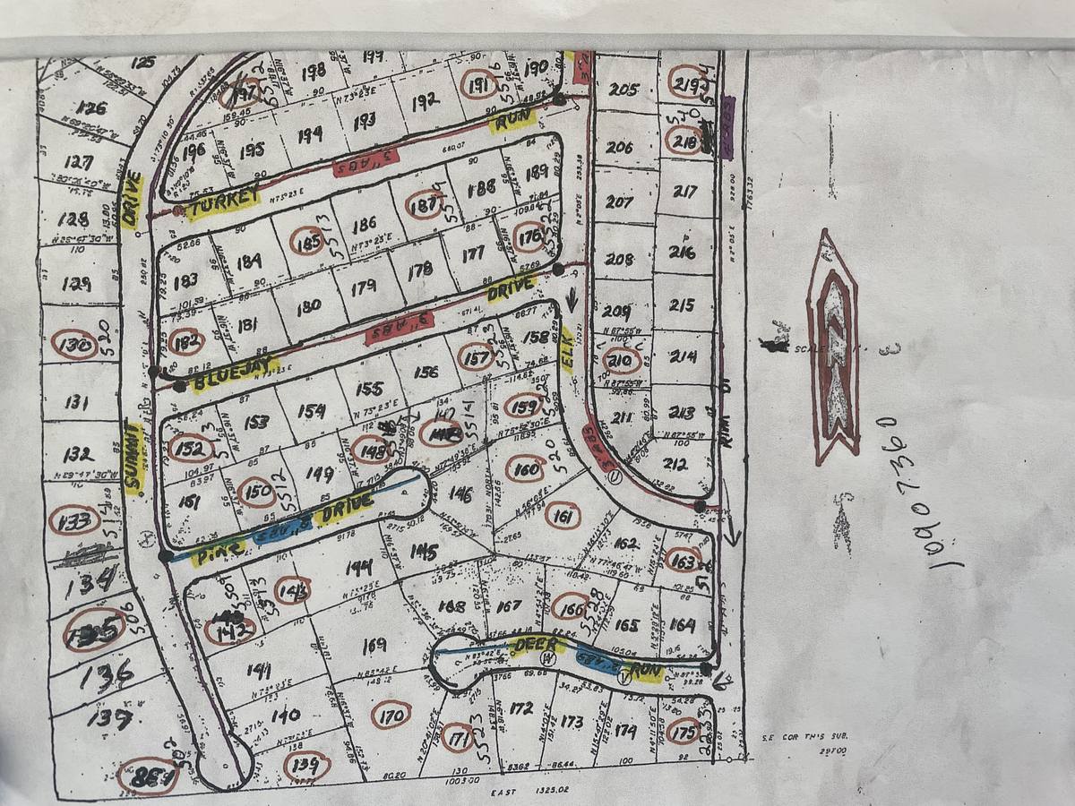 A paper subdivision plat map marked up by hand, with lot numbers circled in red pen, street names highlighted in yellow and blue, and lines traced along the streets in color