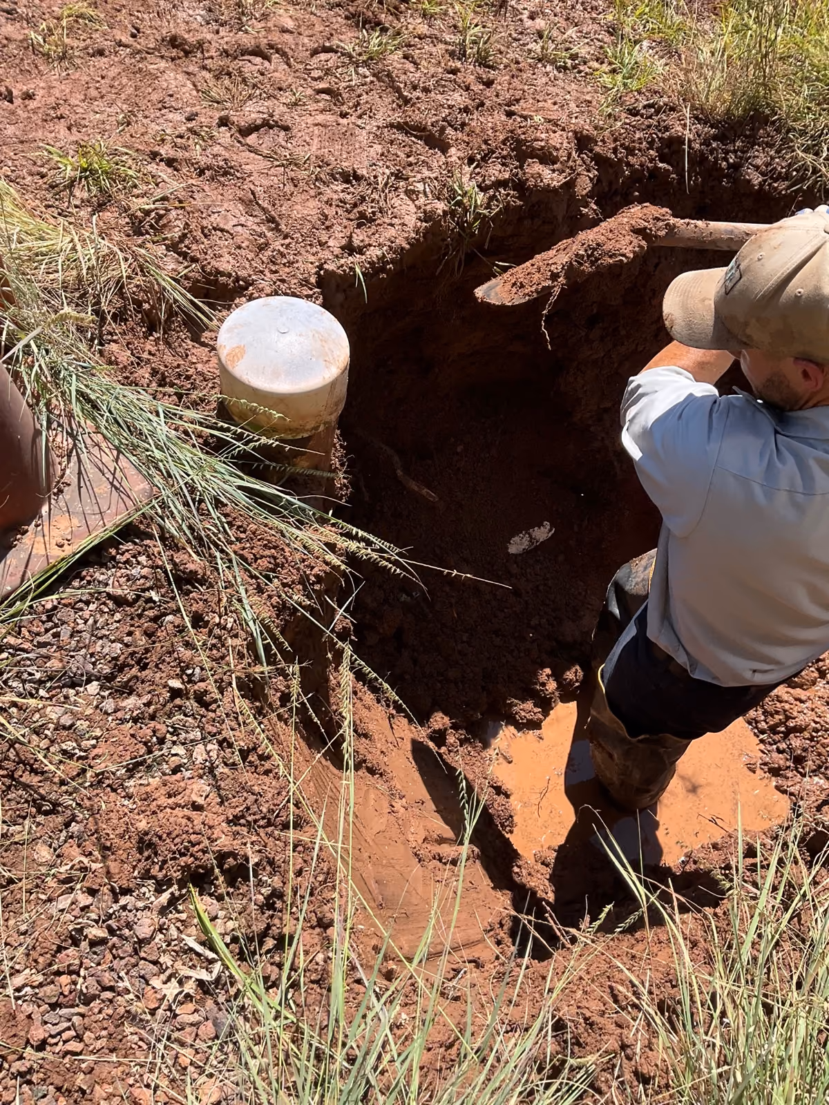 A water operator digging out a service line by hand in an open excavation