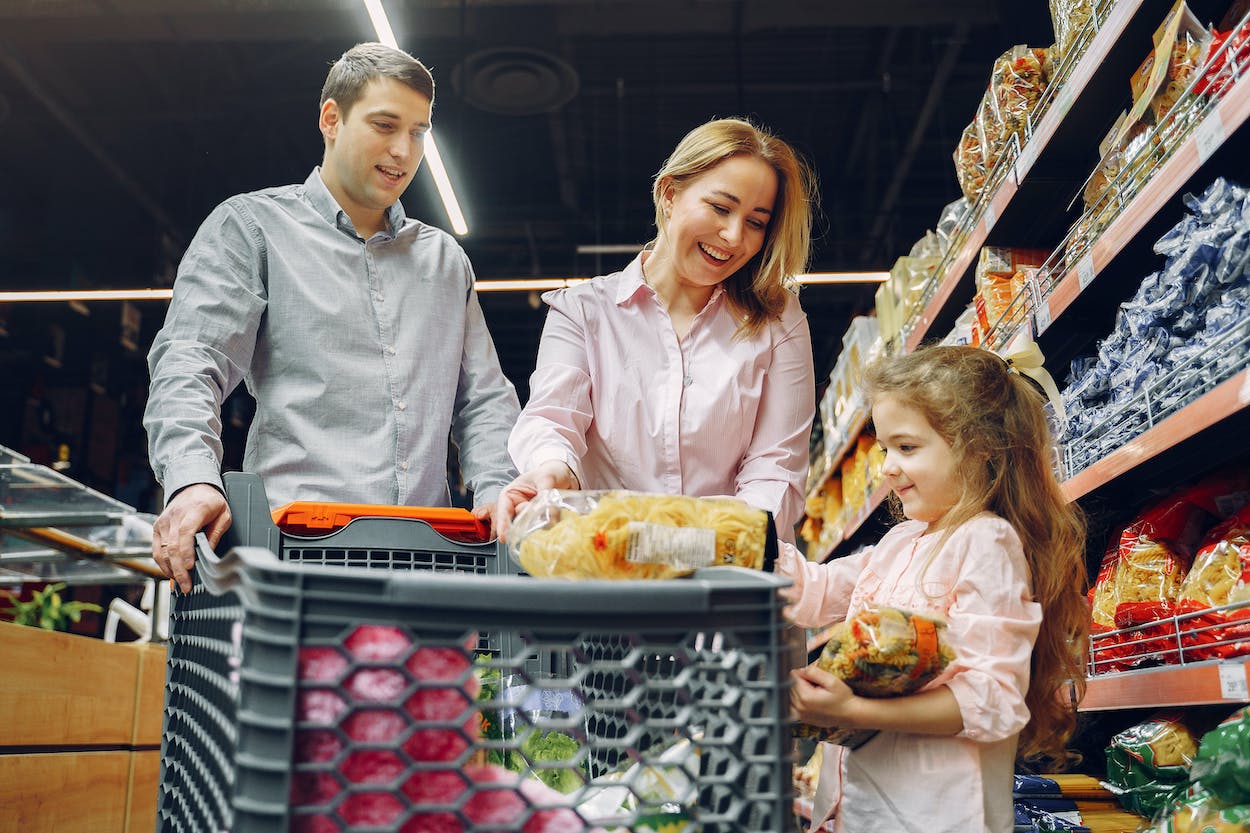 a man and woman with a child looking at a shopping cart
