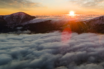 a sunset over clouds and mountains