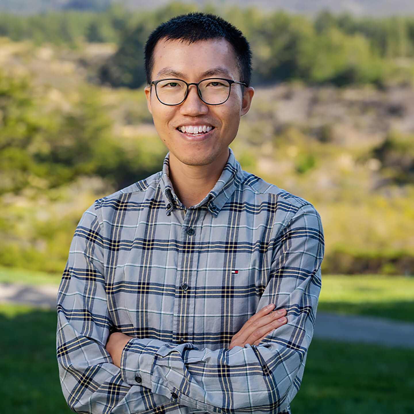 a man with glasses smiling with arms crossed